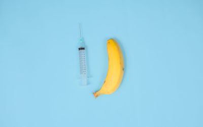 syringe, banana and contraception isolated on blue background